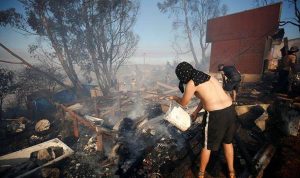 A man throws water to help to extinguish a fire in Valparaiso Kebakaran di Chili hanguskan sekitar 50 rumah dimalam perayaan Natal